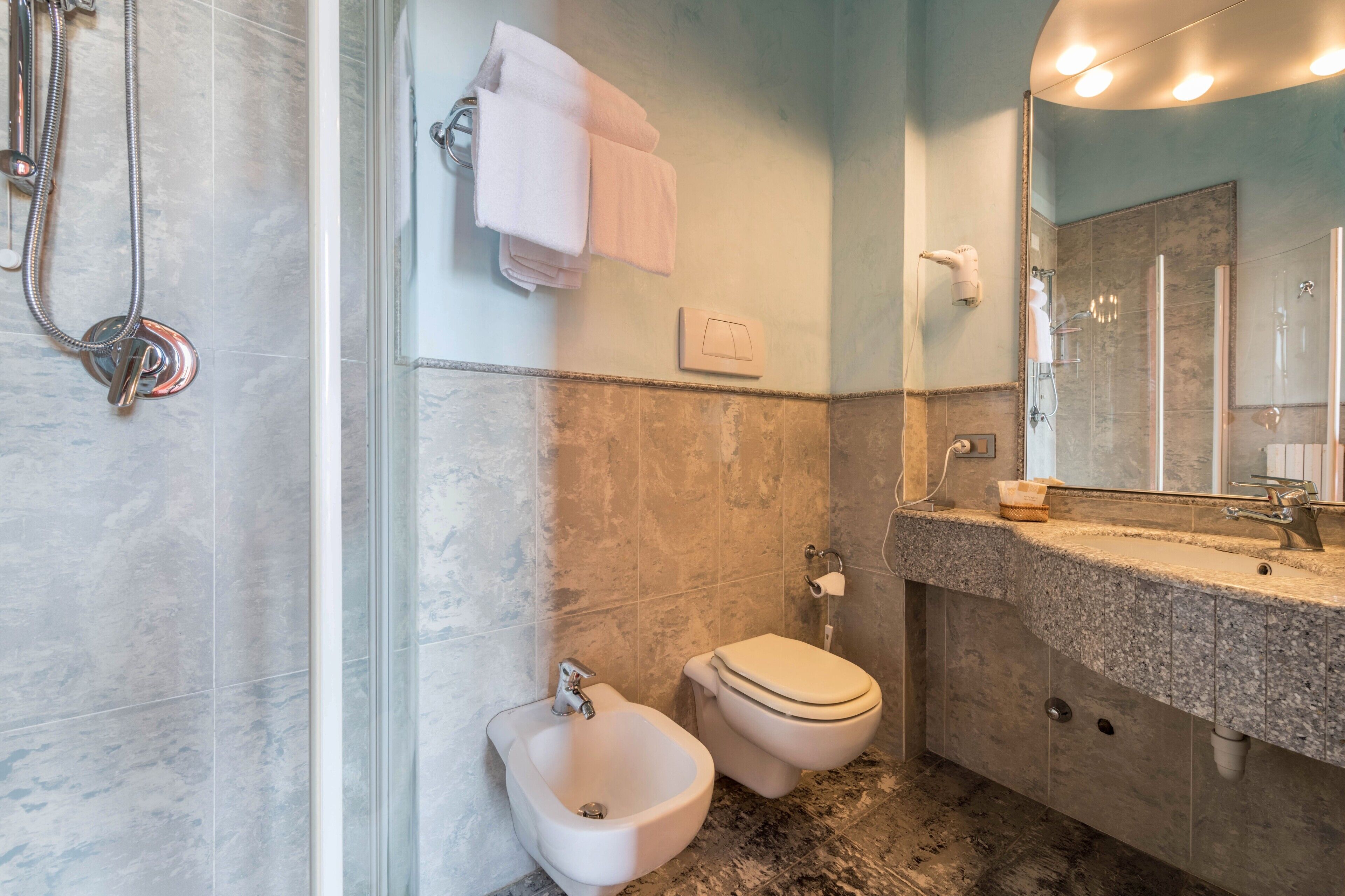 A bathroom with a bidet, toilet, and shower.