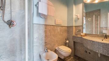 A bathroom with a bidet, toilet, and shower.