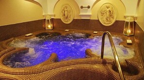 Un bain à remous avec des mosaïques, un robinet en métal et des appliques murales.