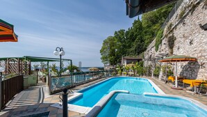 En swimmingpool med en stenmur och utsikt över havet.
