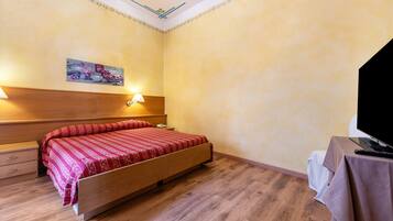 Una camera da letto con un letto di legno, lampade sui comodini, un quadro appeso al muro e una televisione su un tavolino.