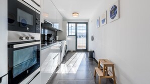 Una cocina moderna con horno integrado, lavadora y un taburete de madera.