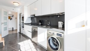 Una cocina moderna con armarios blancos, lavadora integrada y cafetera.