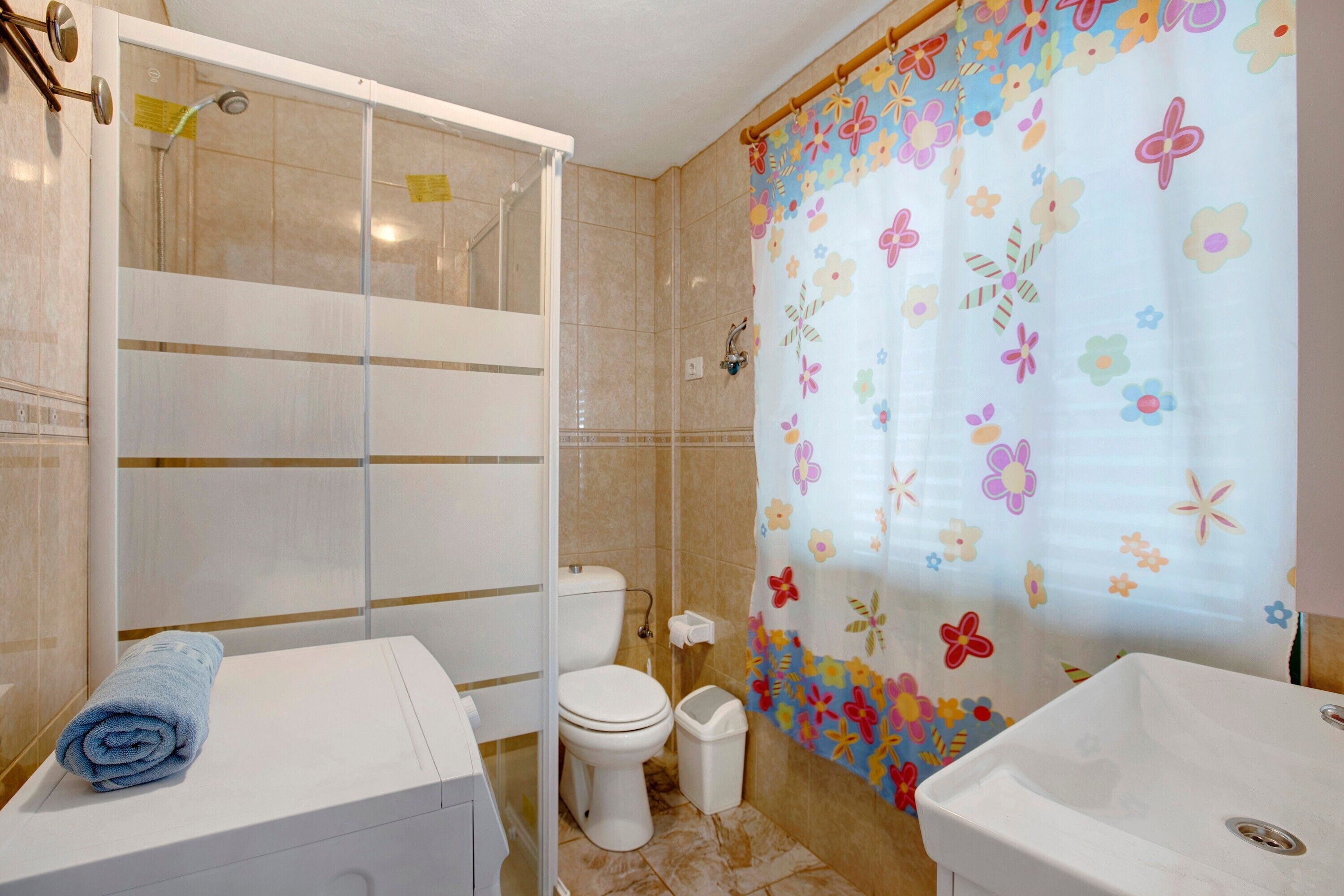 A bathroom with a shower, toilet, sink, and a towel on the counter.