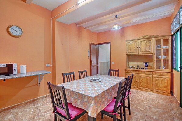 A dining area with a table, chairs, a microwave, and a cabinet.