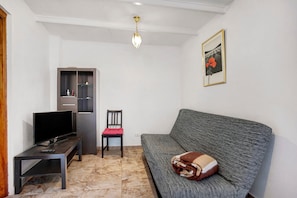 A living room with a sofa, a television on a stand, a chair, a cabinet, and a ceiling light.