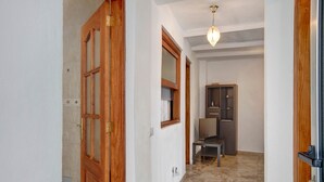 Un pasillo con puertas de madera, suelo de baldosas, una lámpara en el techo y un mueble de color oscuro.