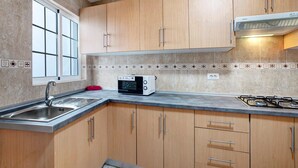 Una cocina con armarios de madera, microondas integrado, estufa a gas y ventana con vistas.