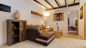 A modern living room with a sofa, a wooden cabinet, a Buddha statue, and a painting. - Vacation Home "Casa Alexis" with Wi-Fi, Terrace & Garden (La lajita)