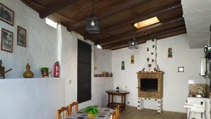 Un comedor con una mesa dispuesta para dos, una chimenea y una pequeña cocina con fregadero y estufa.