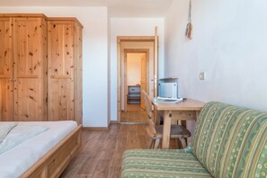 Une pièce comprenant un lit, une armoire en bois, une table à manger avec des chaises et un canapé.