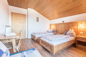 Una stanza con due letti di legno, una scrivania, una sedia e un tavolino con una lampada.