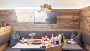 Un comedor con pared de madera, una mesa dispuesta para el desayuno y una lámpara colgante.