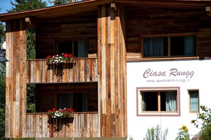 A wooden building with balconies, a sign reading 'Ciasa Rungg', and a website address.