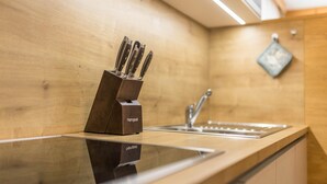 A kitchen with a wooden countertop, a sink, and a knife block. - Apartment 'Ciasa Rungg App Pares' with Mountain View, Garden & Wi-Fi (St.Vigil)