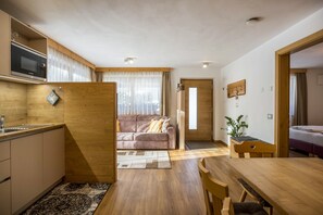 A compact living space with a kitchenette, a sofa, a dining table, and a bed.