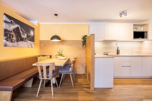 Une cuisine moderne avec des meubles en bois, un coin repas doté d’un banc et une grande fenêtre.