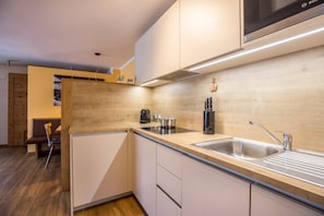 Une cuisine moderne dotée d’un plan de travail en bois, d’un évier en acier inoxydable et d’un four à micro-ondes de la marque Bosch.