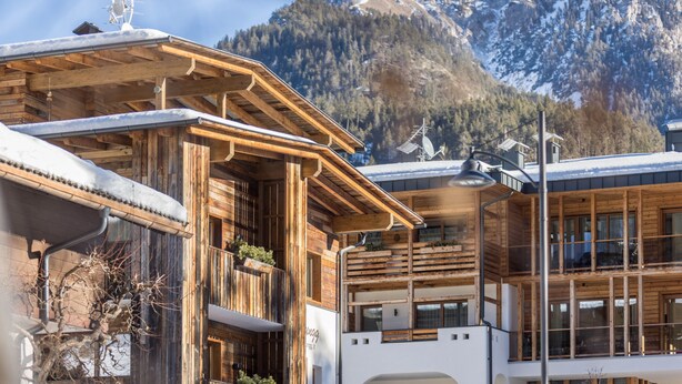 A wooden chalet with a balcony, large windows, and a mountain backdrop. - Apartment 'Ciasa Rungg App Corones' with Mountain View, Garden & Wi-Fi (St.Vigil)