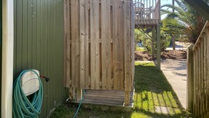A wooden deck with a wooden gate, a hose, and a chair in the background.