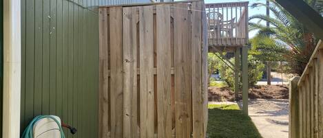 A wooden deck with a wooden gate, a hose, and a chair in the background.