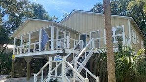 A two-story building with a balcony and a staircase leading to the upper floor. - Sweet M'Ocean | Charming Edisto Beach Retreat: Steps to Shore,Covered Porch,Golf Cart Paradise (Edisto Island)