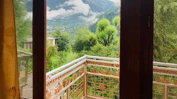 A balcony with a view of a mountainous landscape, including trees and a village below. - Private Room for long and short stay (Manali)