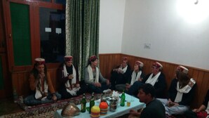A group of people sitting on a patterned carpet in a room with wooden paneling and a green door. - Private Room for long and short stay (Manali)