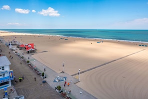 Eine Strandpromenade mit einem Gebäude mit rotem Dach, einem blauen Schild und freiem Blick auf den Ozean.
