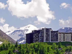 A hotel with multiple floors, surrounded by lush greenery and mountains in the background. - Studio CLASSIC 4 pers, south balcony, heart of Tignes Le Lavachet (Tignes-Le Lavachet)
