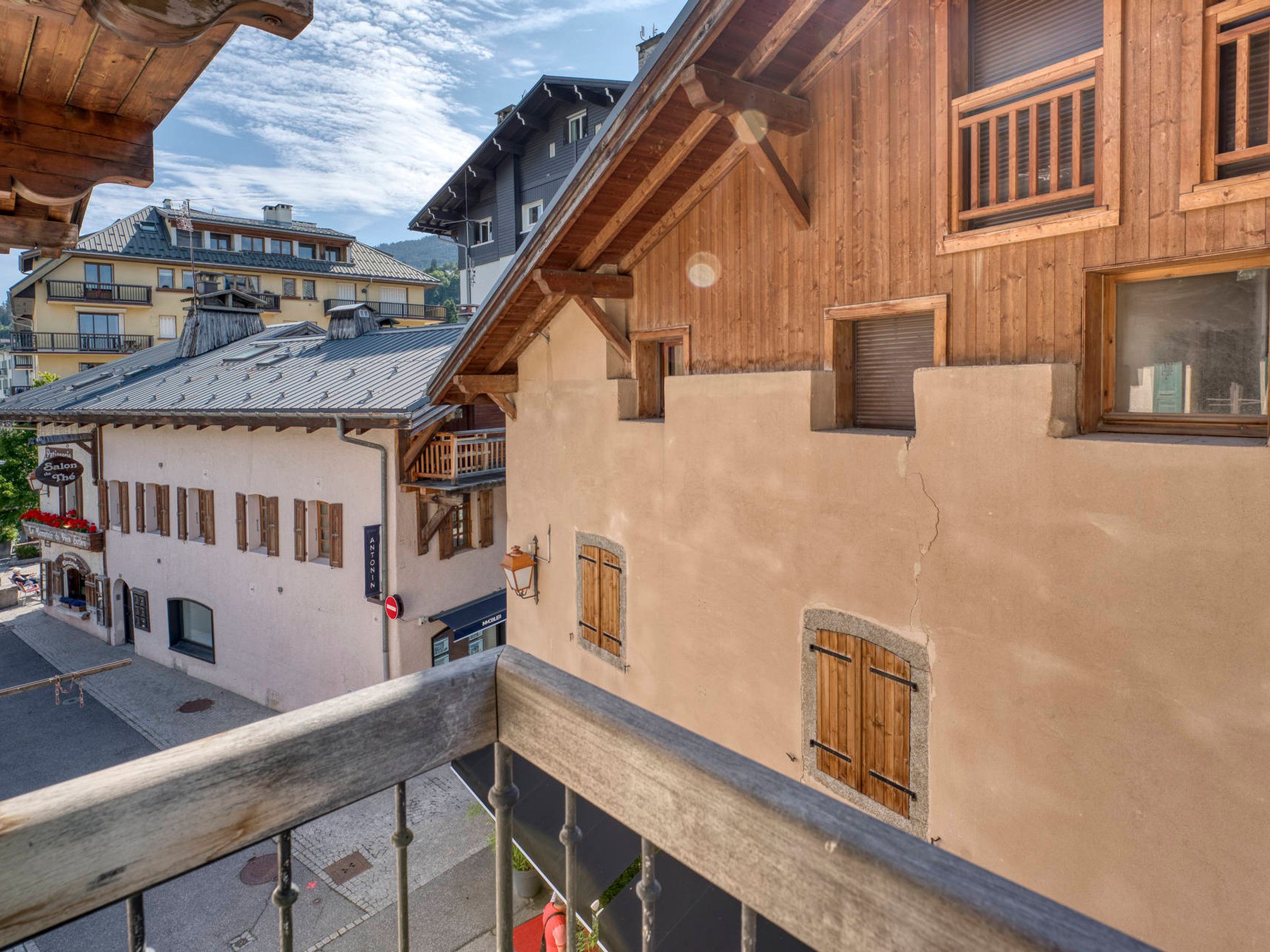 Un edificio de estilo chalete tradicional con un balcón, contraventanas de madera y fachada rústica.
