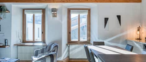 A modern interior with wooden beams, a dining area with a table and chairs, and large windows.