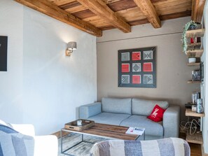 Una sala moderna con un sofá gris, una mesa de centro de madera y una obra de arte en la pared.
