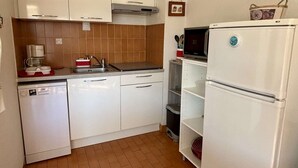 A compact kitchen with white cabinets, a built-in microwave, and a dishwasher.