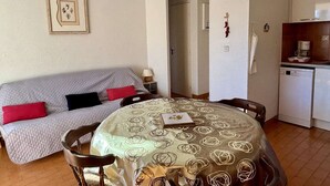 A compact living space with a sofa, a dining table, and a kitchenette.