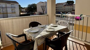 A balcony with a table set for two, chairs, and a view of residential buildings.