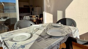 A dining table set with plates and glasses, a window, and a view of a kitchen and dining area.
