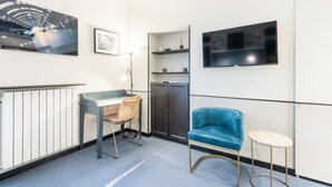 Ein modernes Zimmer mit Schreibtisch, Stuhl, Schrank und einem blauen Sofa.