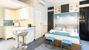 Ein Hotelzimmer mit einem Bett, einem Schreibtisch, einem Stuhl und einem kleinen Hocker.
