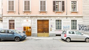 Ein Gebäude mit einer großen Holztür, einem Schild für 'Scelta Ristorante dal 1903' und zwei geparkten Autos davor.