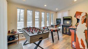 A room with a foosball table, an arcade machine, and a basketball-themed decoration. - Hot Tub, Fire Pit & Game Room: Tobyhanna Home! (Tobyhanna)