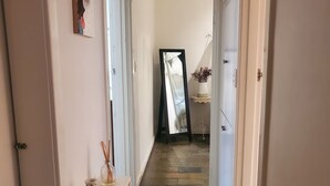 Een gang met een stenen vloer, witte muren en een spiegel die tegen de muur staat.