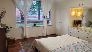 Een slaapkamer met een bed, een kaptafel, een spiegel en een raam met gordijnen.
