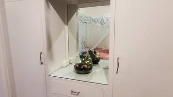 A white wardrobe with a mirror, two drawers, and a glass top.
