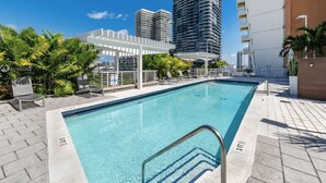 A swimming pool with a white pergola, palm trees, and high-rise buildings in the background. - Elite 1BD/1BTH in Miami W/FREE PARKING! (Miami)