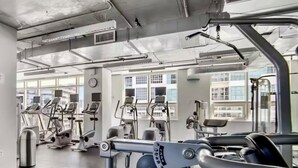 A gym with various exercise equipment, large windows, and a concrete floor. - Elite 1BD/1BTH in Miami W/FREE PARKING! (Miami)