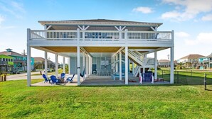 A covered outdoor area with a wooden deck, seating, and a staircase leading to an upper level.