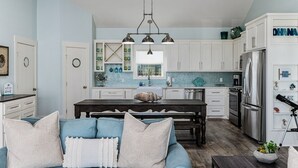 A modern kitchen with white cabinets, a central island, and a stainless steel refrigerator.