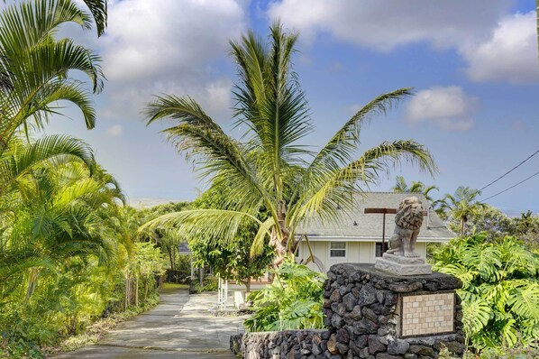 Stroll through lush vegetation to a serene pathway, flanked by a majestic lion statue.