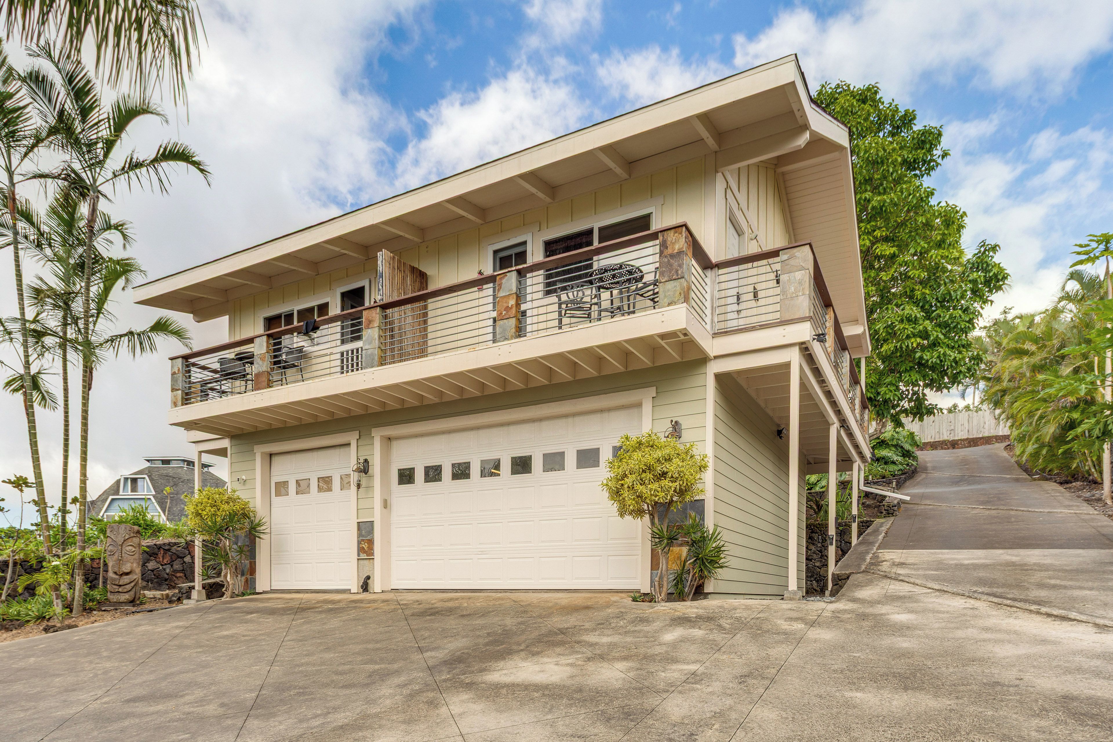 Une maison à deux étages avec un garage, un balcon et une allée.